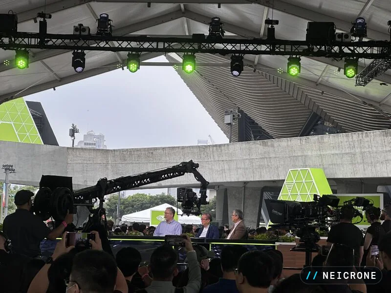 An on-stage conversation in the outdoor pavilion, filmed from a camera crane