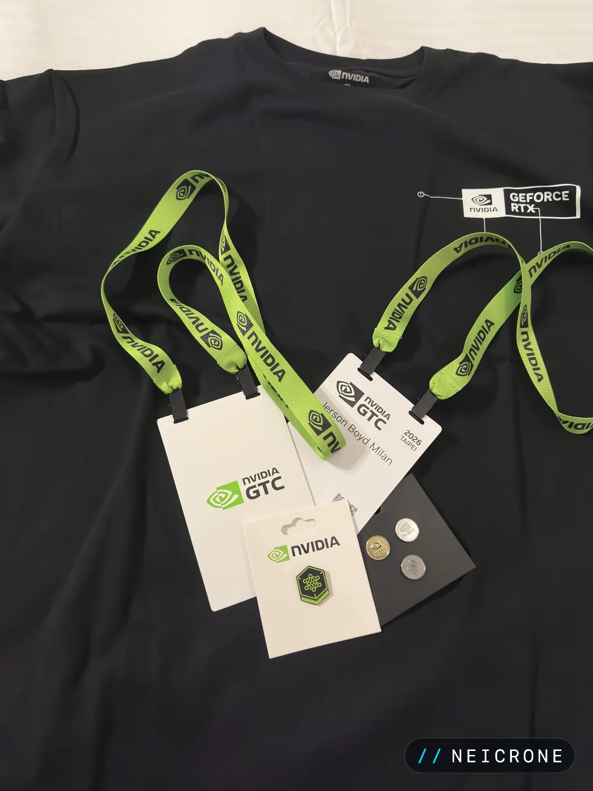 NVIDIA GTC lanyards, badge and pins laid out on a black shirt