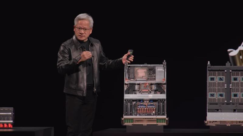 Jensen Huang on stage beside AI factory compute hardware